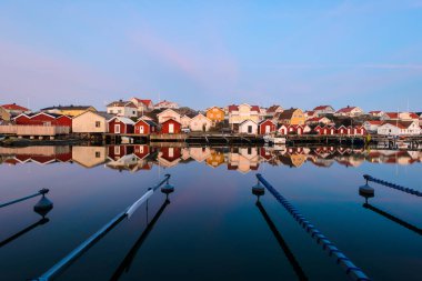 Durgun bir suya yansıyan evlerin önündeki boş liman