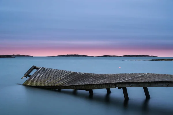 stock image Broken pier on calm lake with dramatic sky