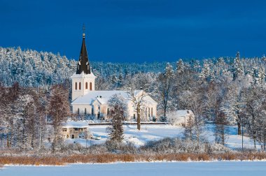 İsveç 'in Hannas kentindeki kilise kışın karla kaplı ağaçlarla çevrili görkemli bir ibadethanedir..
