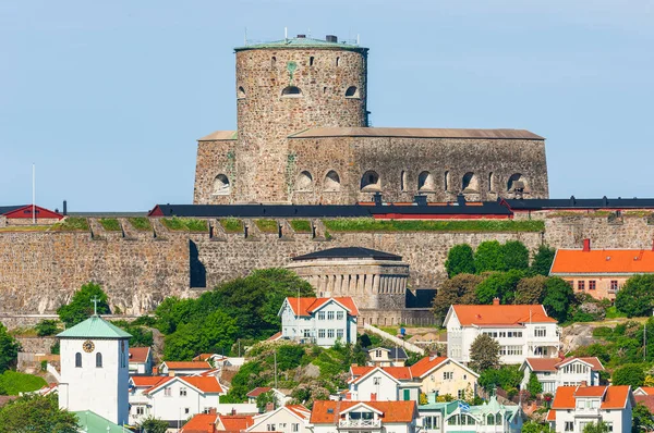 Marstrand, Sweden is a historic town with buildings and houses beneath the blue summer sky. Carlstens Fortress stands tall as an iconic fortification of the past.