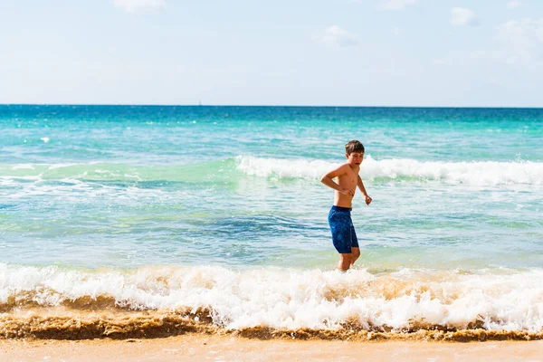 stock image Boy in blue swimming trunks standing by waters edge, Alvor, Algarve, Portugal, Europe