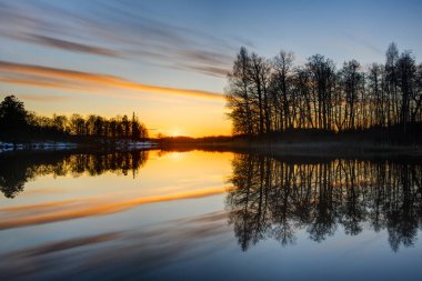 Güzel ağaçların manzarası ve gün batımında sakin bir göl.