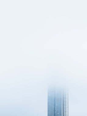 İsveç 'in Göteborg kentindeki sakin bir gökyüzüne karşı kalın ve sisli bir perdeden yükselen uzun bir gökdelenin tepesi. Sabah bulanıklığı modern mimari detayları kısmen gizliyor, sakin ve gizemli bir atmosfer yaratıyor..