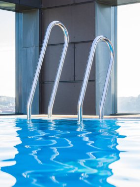 İsveç 'te berrak mavi gökyüzünü yansıtan sakin bir havuz, temiz suya erişimi sağlayan iki adet paslanmaz çelik merdivenle donatılmıştır. Çevresindeki yapı modern mimari ve lüks hissi yayıyor, ferahlatıcı bir yüzüşü davet ediyor. 