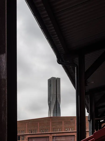 stock image A distinctive skyscraper rises above industrial buildings in Gothenburg, showcasing modern architecture against a gray, overcast sky.