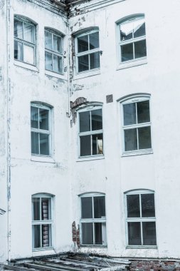 The exterior of an old sanatorium displays cracked walls and broken windows, revealing its abandoned state. Time has worn down the structure, showcasing its history and neglect. clipart