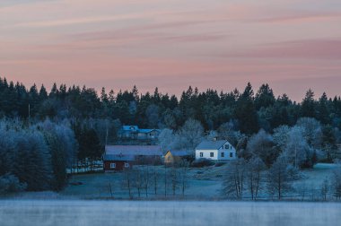 Durgun bir göl, sisle kaplanmış, şafağın ilk ışıklarını yansıtır büyüleyici binalar arka planda yavaşça belirir, İsveç 'in sakin güzelliğini gözler önüne serer.