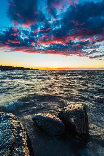 Vallda Sando 'da kıyı manzarasında dingin sulardan çıkan pürüzsüz kayalar bulunur. Gri rengin farklı tonları güzel, sakin bir atmosfer yaratır. Yansıma için mükemmel..