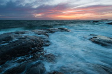 Vallda Sando 'da kıyı manzarasında dingin sulardan çıkan pürüzsüz kayalar bulunur. Gri rengin farklı tonları güzel, sakin bir atmosfer yaratır. Yansıma için mükemmel..
