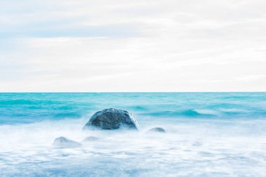 İsveç 'in kıyı şeridi sakin suları şafak vakti yumuşak, bulutlu bir gökyüzünün altında engebeli kayaları nazikçe okşuyor. Huzurlu atmosfer, dalgalar yavaşça içeri girerken yansımayı ve huzuru davet eder..