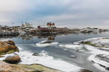 Kış, Göteborg 'un dışındaki kıyı bölgesini karla örtüyor ve sakin bir atmosfer yaratıyor. Kayalık oluşumlar sakin sulara karışırken, kırsal evler manzarayı lekeleyerek güzelliği artırıyor..