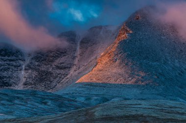 Altın ışık, Rondane Ulusal Parkı 'ndaki engebeli dağlık araziye gölge düşürüyor. Norveç' in alacakaranlıktaki doğal manzarasının güzelliğini ortaya çıkarıyor..