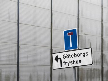 Göteborg 'un soğuk hava deposuna doğru giden bir yol işareti var. Dışı yansıtıcı bir dış görünüşü olan gösterişli bir binanın yakınında. Bölge büyük olasılıkla kentsel ve hareketli, bu da lojistik merkezi gösteriyor..
