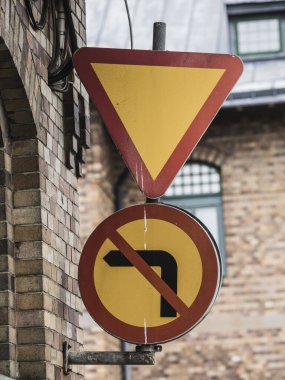 İsveç 'teki bir binada belirgin iki yol işareti sergileniyor. Bir tabela sürücülere teslim olmalarını öğretirken, diğeri sola dönmeyi yasaklıyor. Kentsel mimari içerik ekler.