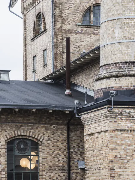 Göteborg 'daki tarihi bir sanayi binasının ön cephesinde karmaşık tuğla desenler, büyük pencereler ve kendine özgü bir baca bulunur. Bu yapı sanayi mirasını yansıtıyor..