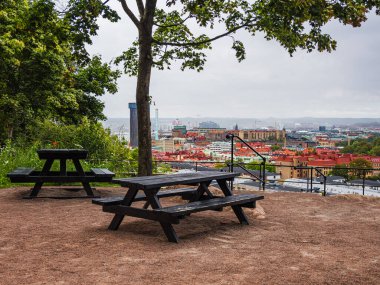 Piknik masasında oturup Göteborg 'un çarpıcı manzarasını seyretmek. Çimento, bulutlu bir günde aşağıdaki renkli şehri vurguluyor..