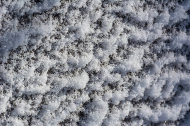 Buz ya da duvardaki beyaz taze kar dokusu. Gevşek kar taneleri yakın plan. Kış - Aralık, Ocak, Şubat. Beyaz ve mavi renkler. Işık ve gölge oyunu. Soğuk, güneşli kış havası.