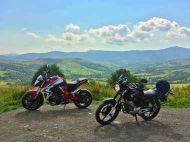 Motosiklet seyahatleri ilkbaharda, yazda, sonbaharda. Kırsal, doğa, dağlar, arka planda mavi gökyüzü. Mola için yolun kenarına park edilmiş siyah motosiklet. Ekstrem, eğlence, eğlence, yaşam tarzı.