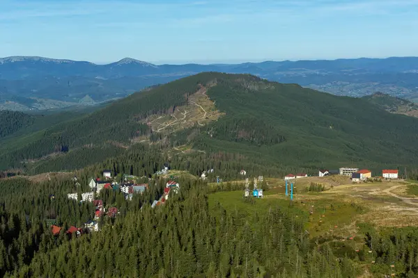 Küçük bir köy, yerleşim yeri, güneşli havada mavi gökyüzüne karşı Karpat Dağları 'nda tatil köyü. Dragobrat, Transcarpathia, Ukrayna. Açık hava eğlencesi ve seyahat. Geçmişi. Tepeler ve ormanlar.