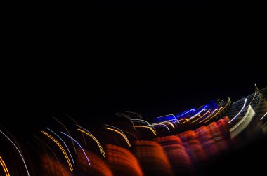 Neon şehir ışıkları. Siyah bir arka planda gece şehrinin bulanık parlaklığı. Gece veya akşam üzeri. Parlak kavisler. Seyahat, turizm. Uzhgorod. Boş alanı kopyala.