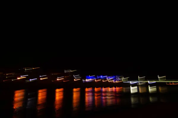 Neon şehir ışıkları. Siyah bir arka planda gece şehrinin bulanık parlaklığı. Gece veya akşam üzeri. Parlak kavisler. Seyahat, turizm. Uzhgorod. Boş alanı kopyala.