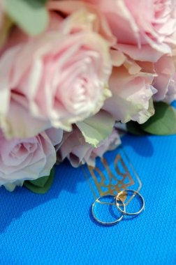 Evlilik kaydı Ukrayna Nüfus Dairesinde. Mavi arka planda iki altın yüzük ve üç dişli armalı arma. Bir buket gül. Aşık olmak, düğün, ilişkiler, birlikte.