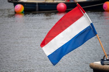 Hollanda bayrağı rüzgârda dalgalanıyor. Kırmızı, Beyaz ve Mavi. Ulusal gurur ve birlik. Hollanda 'daki vatanseverlik ruhu. Arka planda gökyüzü, su veya binalar.