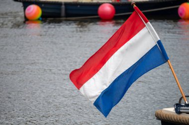 Hollanda bayrağı rüzgârda dalgalanıyor. Kırmızı, Beyaz ve Mavi. Ulusal gurur ve birlik. Hollanda 'daki vatanseverlik ruhu. Arka planda gökyüzü, su veya binalar.