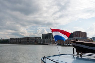 Hollanda bayrağı rüzgârda dalgalanıyor. Kırmızı, Beyaz ve Mavi. Ulusal gurur ve birlik. Hollanda 'daki vatanseverlik ruhu. Arka planda gökyüzü, su veya binalar.