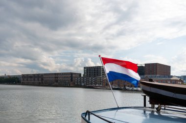 Hollanda bayrağı rüzgârda dalgalanıyor. Kırmızı, Beyaz ve Mavi. Ulusal gurur ve birlik. Hollanda 'daki vatanseverlik ruhu. Arka planda gökyüzü, su veya binalar.