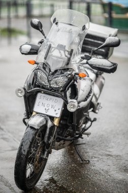 Büyük siyah bir tur motosikleti karla kaplıdır. Motosiklet sezonunun sonu, kış. 