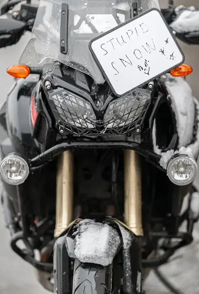 Büyük siyah bir tur motosikleti karla kaplıdır. Motosiklet sezonunun sonu, kış. 