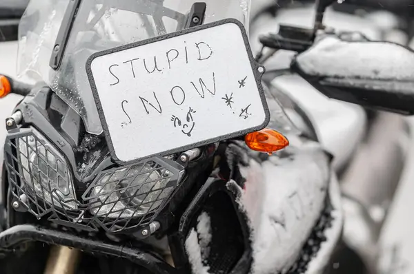 Büyük siyah bir tur motosikleti karla kaplıdır. Motosiklet sezonunun sonu, kış. 
