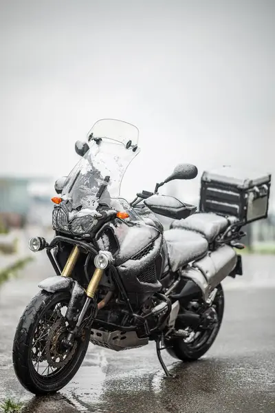Büyük siyah bir tur motosikleti karla kaplıdır. Motosiklet sezonunun sonu, kış. 