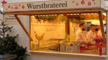 Geleneksel Noel pazarında Noel evinde sosis pişiren 4K.2 erkek. DÜZSELDORF, GERMANY, 26 DEC 2022. Yüksek kalite 4k görüntü