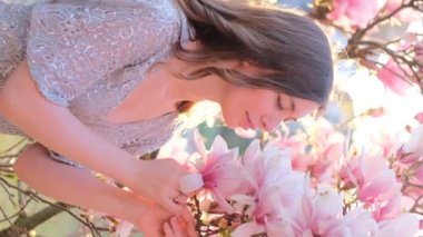 Manolya çiçeği koklayan ve tutan güzel bir kadının bahar güzelliği portresi. Bahar çiçeği. Manolya ağacının yanında giyinmiş muhteşem romantik bir kız. Yüksek kalite