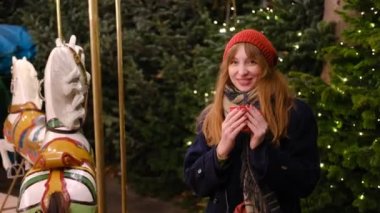 4 bin. Kırmızı bereli ve ceketli atlıkarınca yakınlarındaki Noel pazarında kızıl saçlı güzel bir kadın kırmızı bir kupadan gülümseyip sıcak çikolatanın tadını çıkarıyor. 