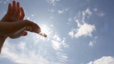 Eller güvercini betimliyor. İnsan eli performansında bir kuşun kanatları. Gökyüzündeki el ve güneş parlıyor