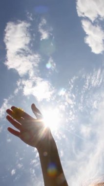 El, güneşli bir gökyüzünün arka planına el sallıyor. Gökyüzündeki el ve güneş parlıyor