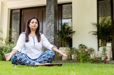 Hintli Olgun Kadın ev bahçesinde yoga yapıyor