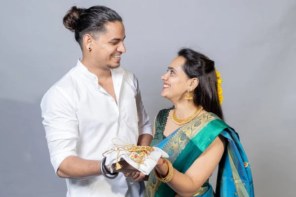 Indian couple holding gold jewelry, ornaments - Asset or Gold Loan concept. Indian couple looking each other with jewelers in hand