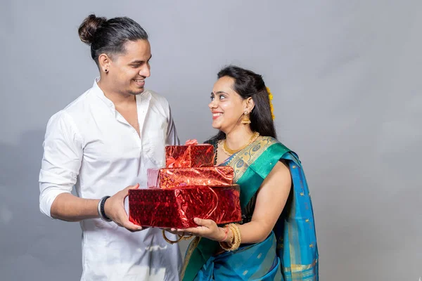 Portrait on happy young indian couple holding Gift box looking each other, Diwali Festive offer concept
