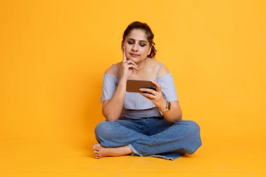 Telefondan oyun oynayan heyecanlı Hintli kadın telefon ekranına bakan neşeli kadın.