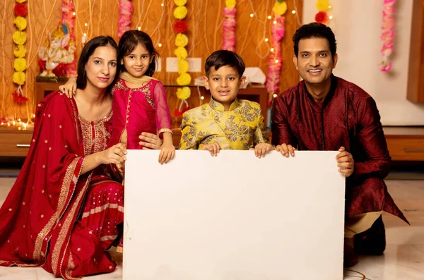 portrait of indian Family indoor looking towards the camera with sign board ,Indian family in ethnic wear Advertisement festival concept