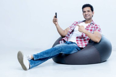 Hintli yakışıklının tam boy fotoğrafı rahat çantalı parmaklar mobilete. Reklam konsepti.