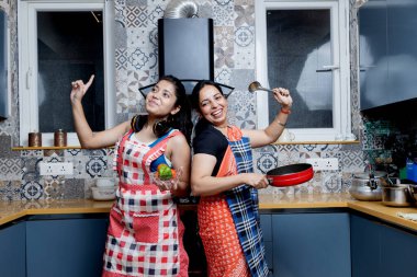 Hint anne ve kızı mutfakta eğleniyor, anne ve kız birlikte yemek pişiriyor.