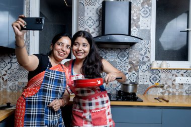 Hint anne ve kızı mutfakta eğleniyor, anne ve kız birlikte yemek pişiriyor ve selfie çekiyorlar.