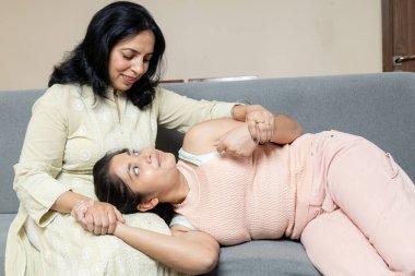 Hintli bir anne, genç kızına elini tutarak güven veriyor, anne de adet günlerinde kızını destekliyor.