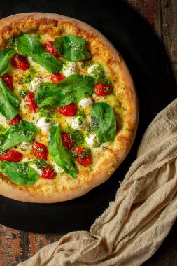 Buffalo Mozzarella Pizza. Domates soslu Napoli pizzası, mozzarella peyniri, pesto sosu, roka ve vişneli domates.