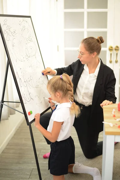 A  teacher teaches her young daughter to paint with colorful pens in the school classroom. concept of child rearing education By being a creative and artistic child.